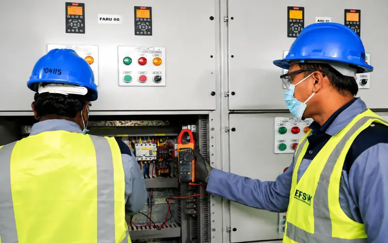 EFS Facilities Services Group technicians performing electrical maintenance and technical operations in a facility control room