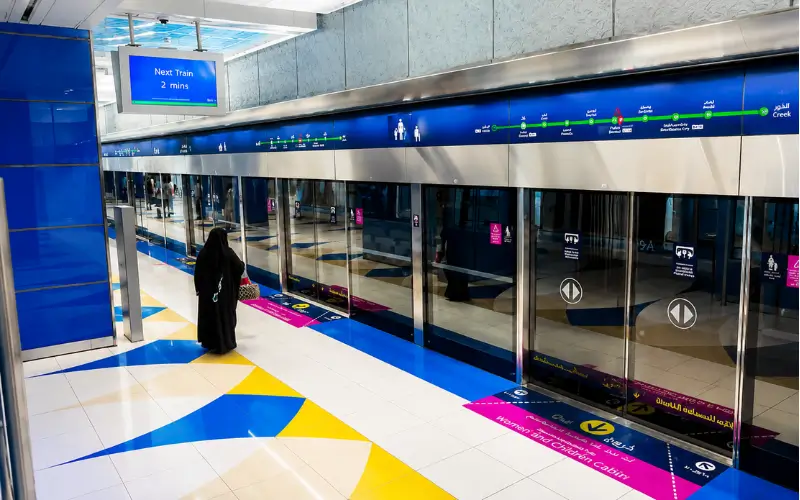 BurJuman Metro Station platform with modern glass doors, Dubai Metro signs, and passenger waiting area